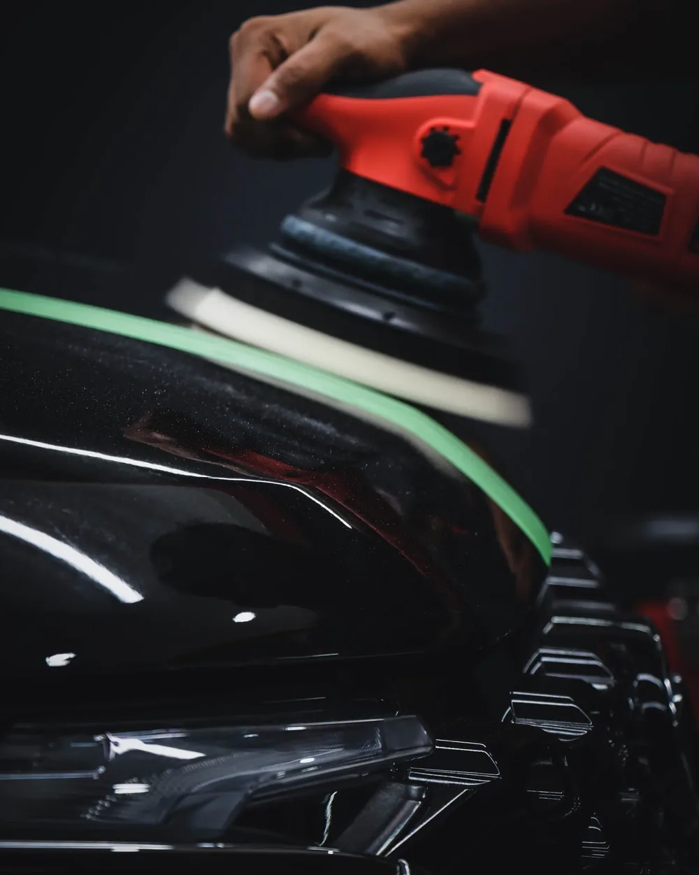A machine polisher working a dark panel