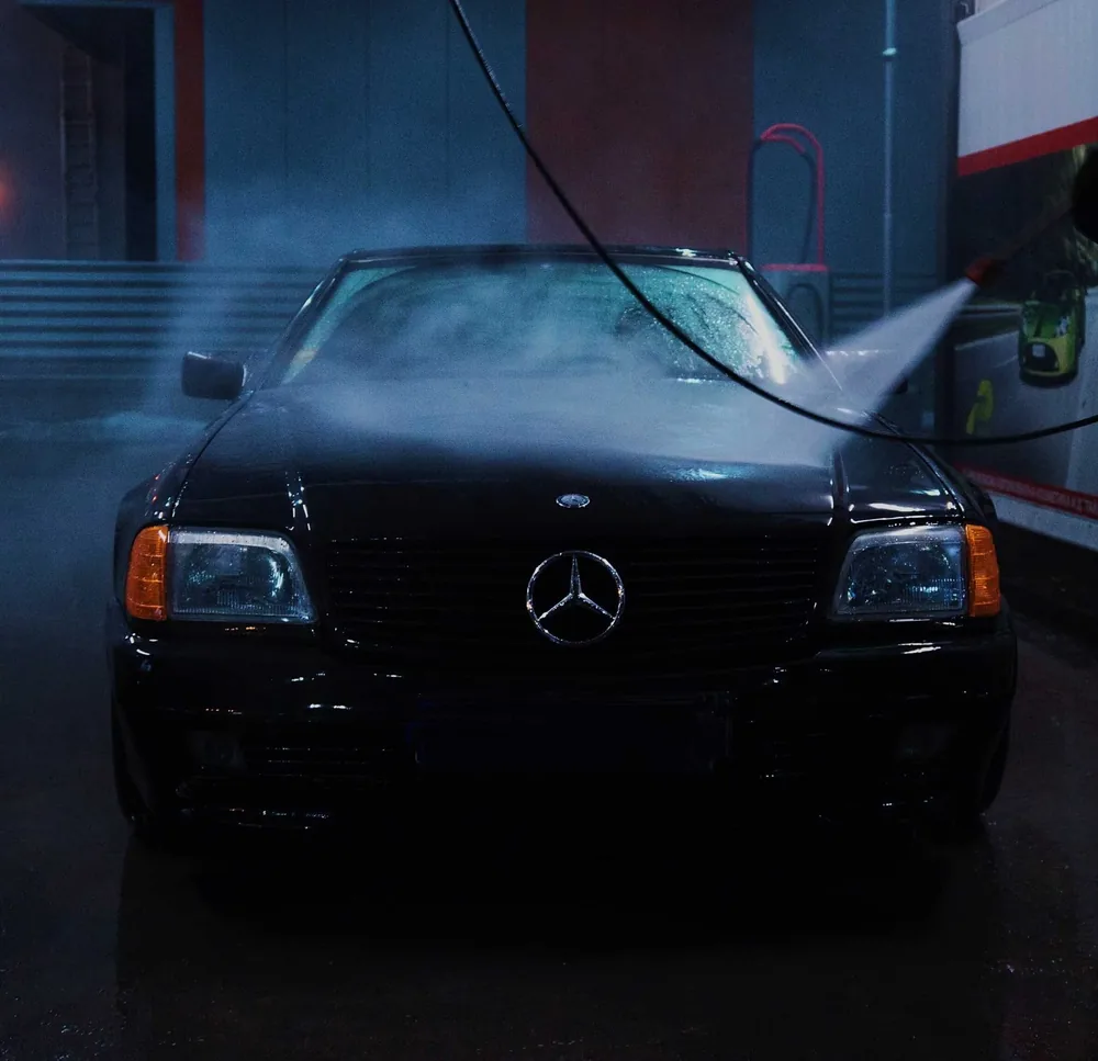 A black Mercedes being rinsed at night