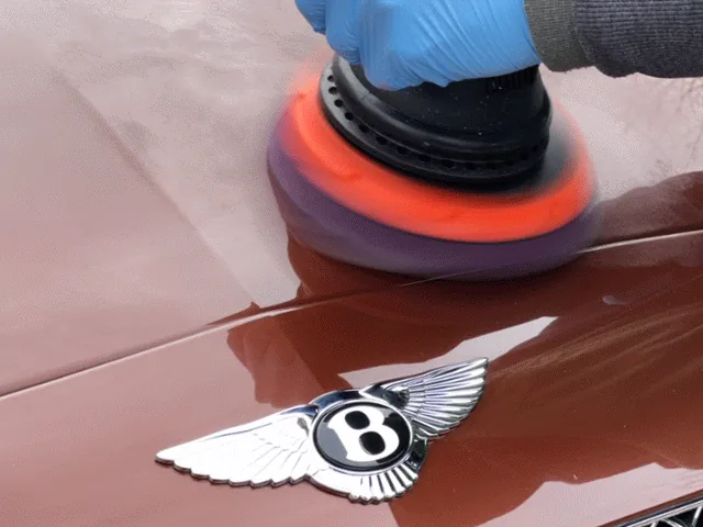 A dual-action polisher finishing the bonnet of a Bentley